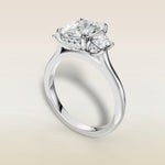 Cushion Three Stone Hidden Halo engagement ring in white gold, angled view