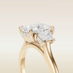 Cushion Three Stone Hidden Halo engagement ring in yellow gold, basket close up
