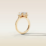 Cushion Three Stone Hidden Halo engagement ring in yellow gold, angled side view