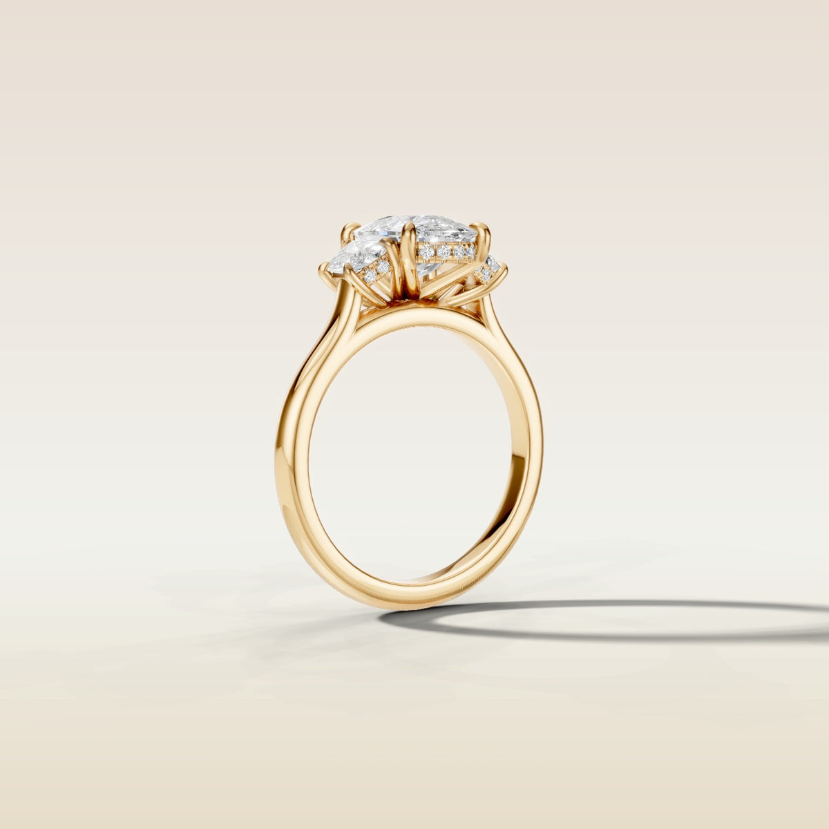 Cushion Three Stone Hidden Halo engagement ring in yellow gold, angled side view