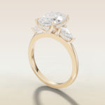 Oval Tulip Three Stone Hidden Halo engagement ring in yellow gold, angled side view
