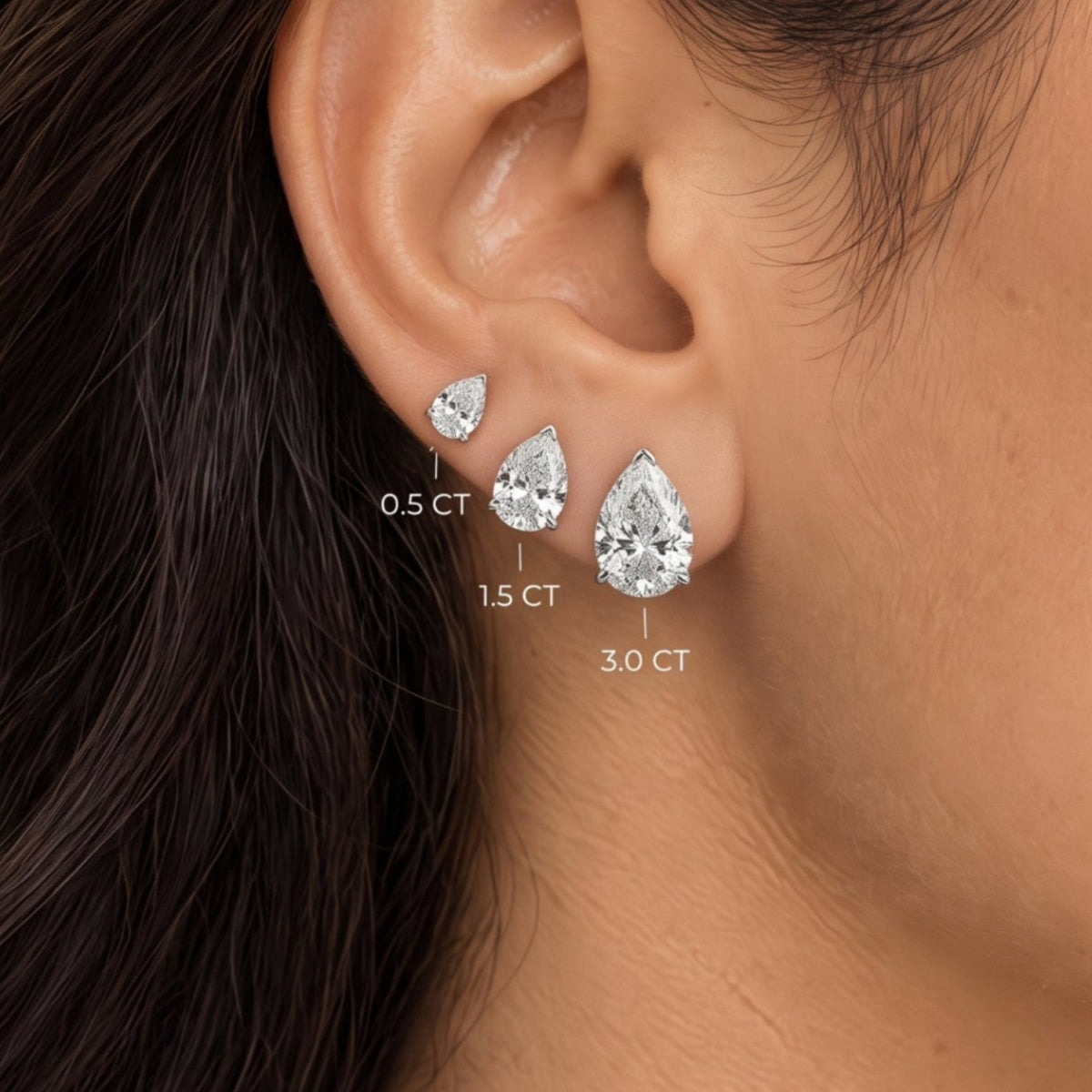 Pear shaped lab grown diamond stud earrings worn in 0.5, 1.5 and 3.0 carat sizes